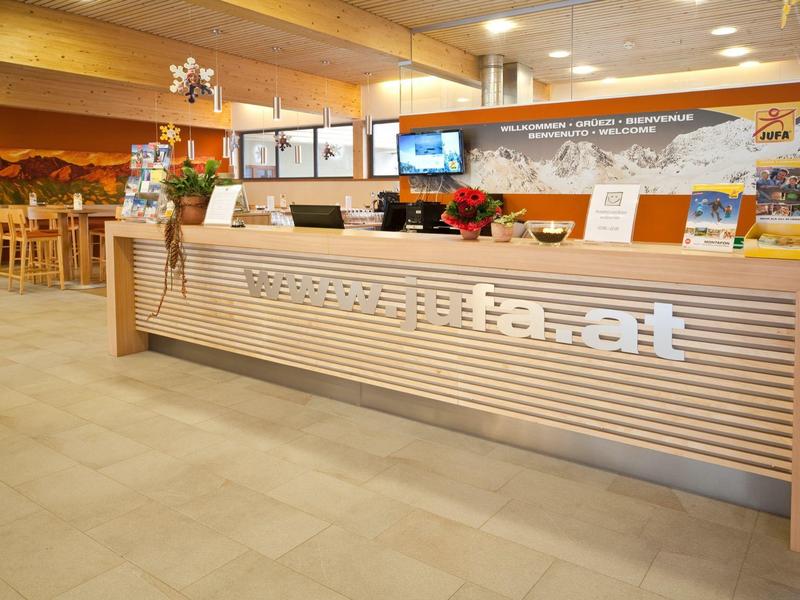 Bright hotel lobby with modern reception desk and wooden ceiling.