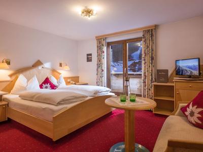 Chambre d'hôtel confortable avec lit double, meubles en bois et vue par la fenêtre.