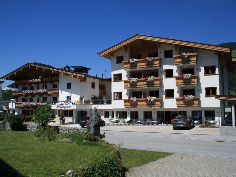 Deux hôtels à plusieurs étages avec balcons et montagnes en arrière-plan par journée ensoleillée.