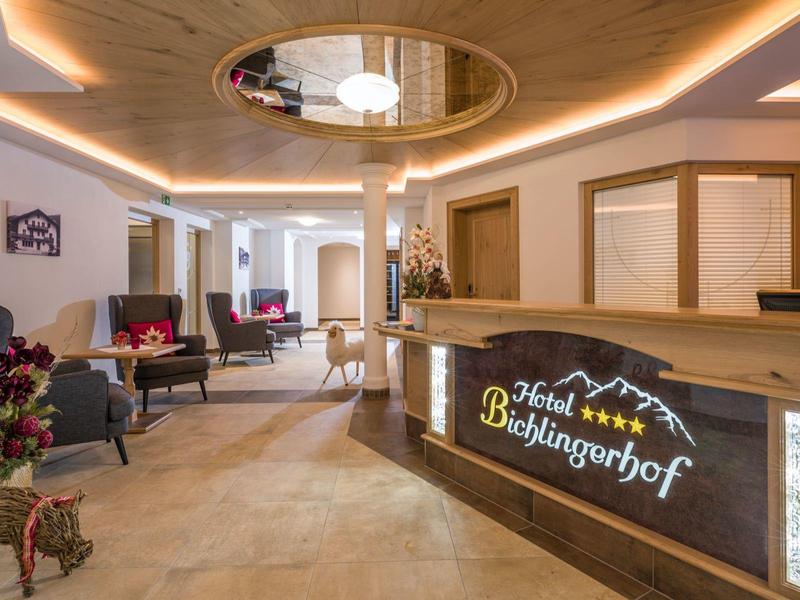 Réception d'hôtel moderne avec comptoir éclairé, coin salon et éléments en bois.