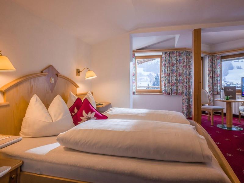 Chambre d'hôtel confortable avec deux lits simples, décor en bois et télévision.