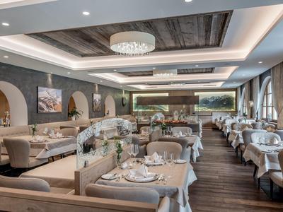 Ristorante elegante con tavoli apparecchiati, sedie e lampadari in un ambiente moderno.