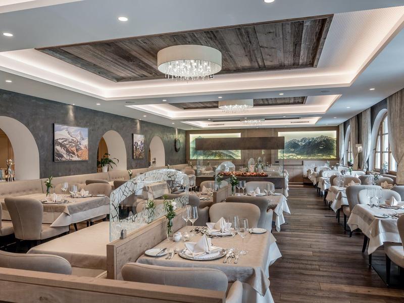 Elegant restaurant with set tables, comfortable chairs, and modern lighting.