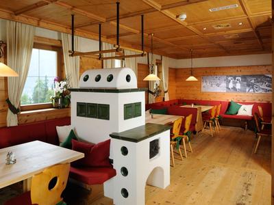 Accogliente sala da pranzo con pareti in legno, mobili in legno e stufa tradizionale in ceramica.