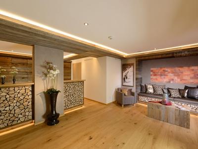 Luminoso atrio dell'hotel con pavimento in legno, zona salotto accogliente e mucchi di legno decorativi alle pareti.