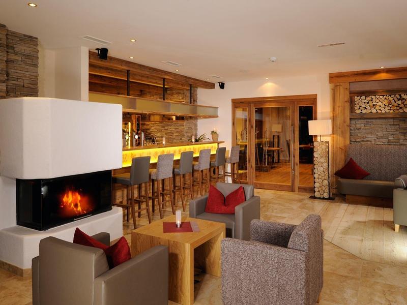 Accogliente area lounge dell'hotel con camino, gruppi di sedute e calda decorazione in legno.