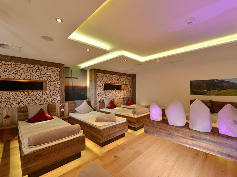 Accogliente sala relax con poltrone e letti, illuminazione soffusa, pavimento in legno.