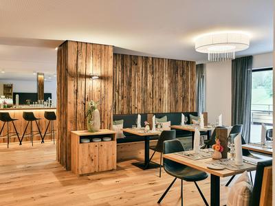 Restaurant moderne avec accents en bois, tables élégantes et bar en arrière-plan.