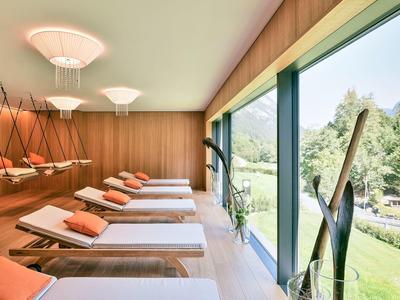 Modern relaxation room with loungers and large windows overlooking green nature.