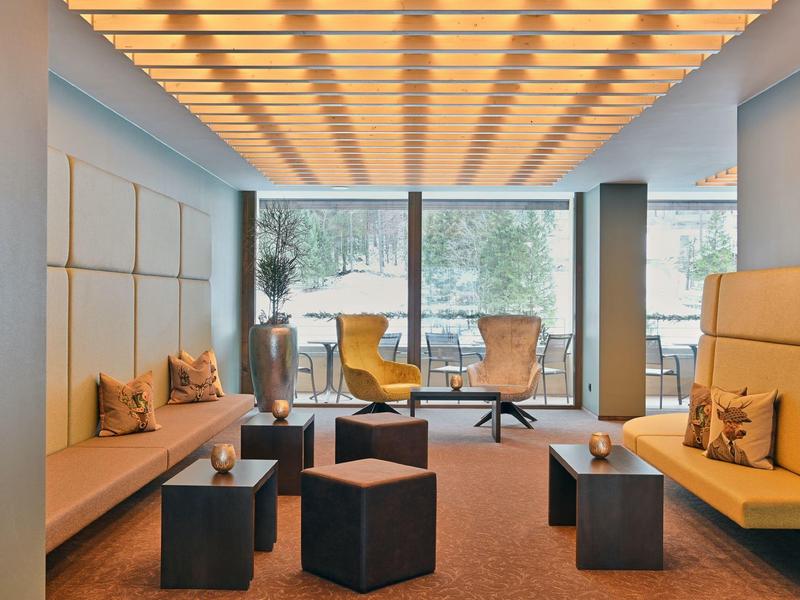 Modern hotel lobby with comfortable armchairs, sofas, and large window with a view.