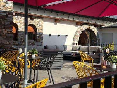 Terrasse confortable avec chaises jaunes, canapé gris et grand parasol par une journée ensoleillée.