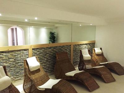 Espace détente avec chaises longues en rotin et serviettes devant un miroir dans un hôtel.