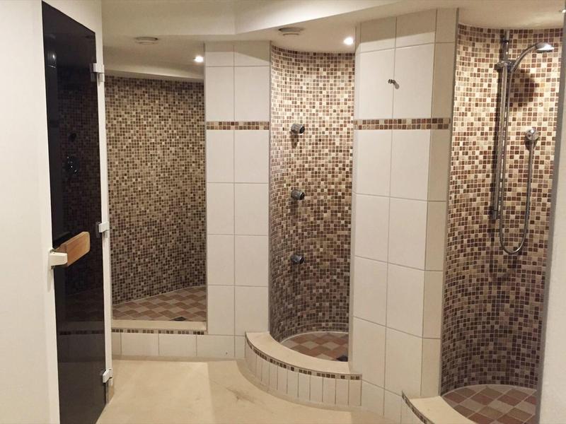 Douche moderne avec carrelage blanc et motif en mosaïque dans la salle de bain de l'hôtel.