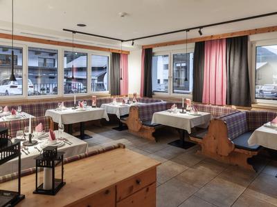 Ein gemütlicher Restaurantbereich mit Holzmöbeln und großen Fenstern mit Blick auf umliegende Gebäude.