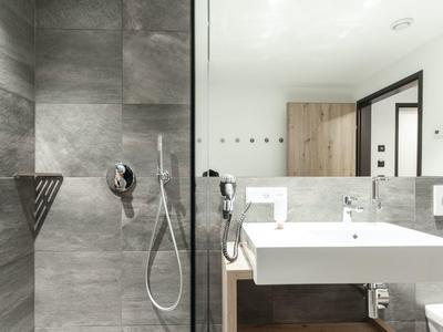 Moderner Hotelbadezimmer mit großer weißen Waschbecken und grauen Fliesen.