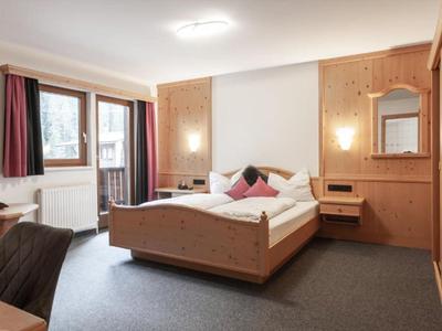 Gemütliches Hotelzimmer mit Holzinterieur, Balkon und modernem Doppelbett.