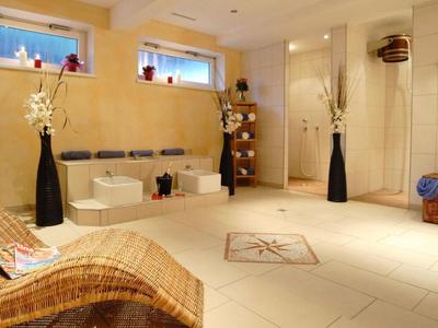 Helles Wellnesszimmer mit Whirlpool, großen Vasen und entspannendem Liegestuhl.