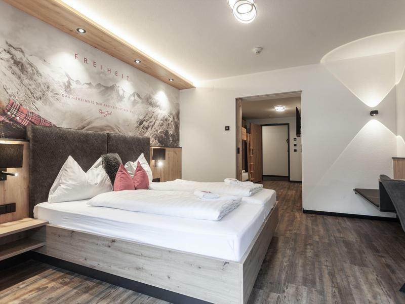 Modernes Hotelzimmer mit Doppelbett, Holzboden und stilvoller Wanddekoration.