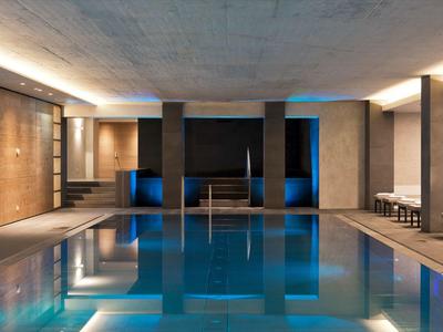 Moderner Innenpool mit blauer Beleuchtung und bequemen Sitzgelegenheiten in einem Hotel.