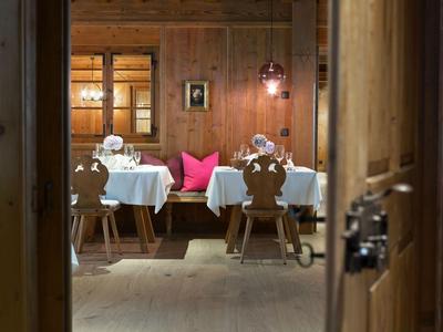 Rustikales Esszimmer mit Holzmöbeln, weißen Tischdecken und pinken Kissen an der Bank.