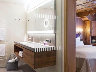 Modernes Badezimmer mit Glasduschwand, Holzwaschbeckenunterschrank und angrenzendem Schlafzimmer.