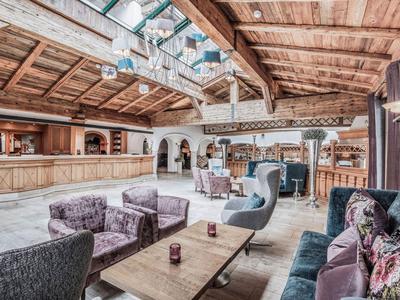 Gemütliche Hotel-Lounge mit hölzernen Balkendecken, Polstermöbeln und einem langen Holztisch.