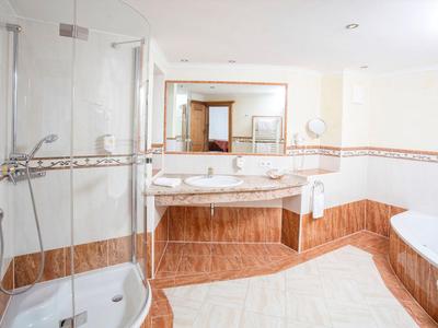 Helles Badezimmer mit Dusche, Doppelwaschbecken und Badewanne, helle Wände und braune Fliesen.