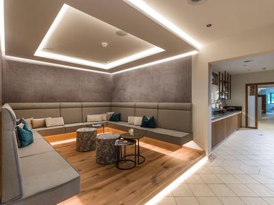 Moderner Hotel-Lounge-Bereich mit grauen Sofas, Holzboden und beleuchtetem Decken-Design.