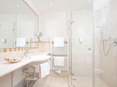 Helles, modernes Badezimmer mit großer Glasdusche und weißen Handtüchern am Handtuchwärmer.