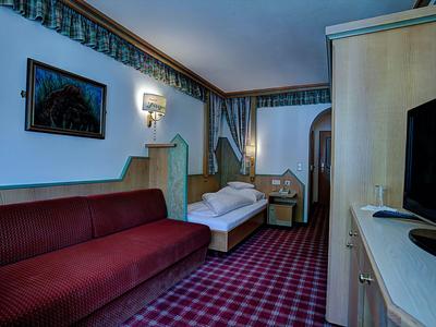 Pokój hotelowy z dwiema sofami, wykładziną i telewizorem na szafce