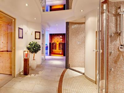 Nowoczesny korytarz hotelowy z kamienną podłogą, podświetlonymi drzwiami i szklaną prysznicem po prawej