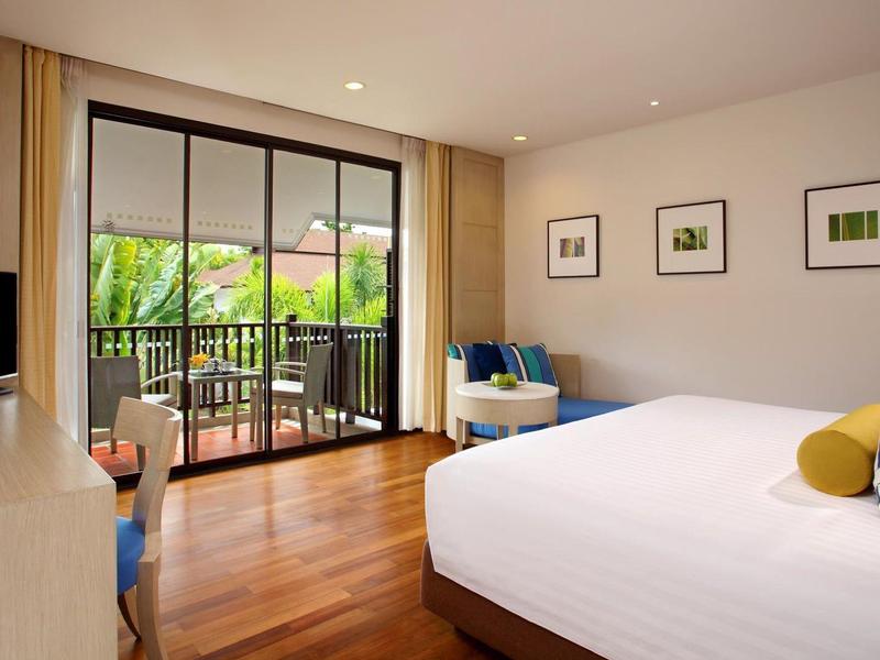 Helles Schlafzimmer mit großem Bett, Holzboden, Balkon und moderner Einrichtung in neutralen Farben.