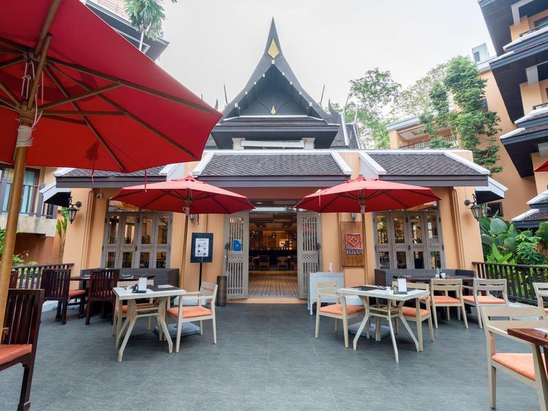Einladender Außenbereich eines Restaurants mit roten Sonnenschirmen und traditionellem thailändischem Gebäude.