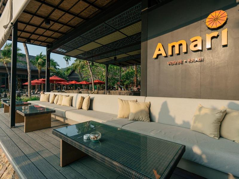 Außenlounge mit beigen Sofas, Glastisch und grauer Holzterrasse vor dem Amari Hotel.