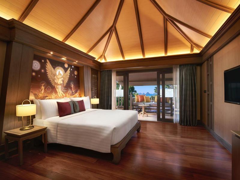 Luxuriöses Holzschlafzimmer mit großer Glasschiebetür und Blick auf Terrasse und Meer.