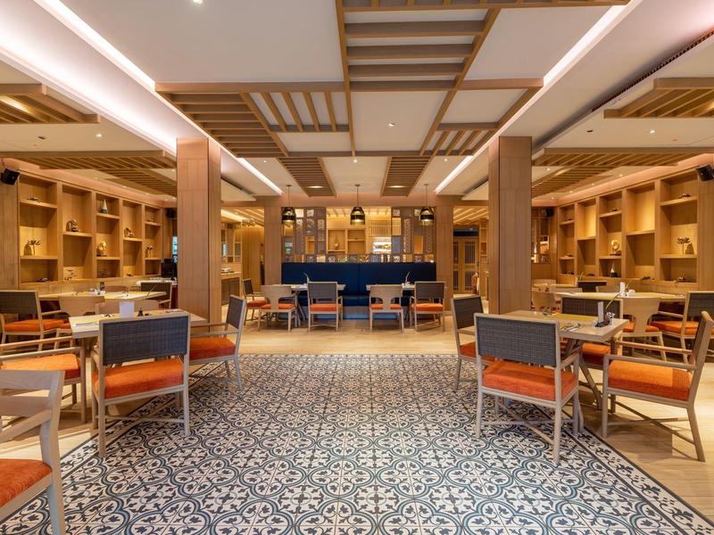 Großer Lesesaal mit Holzmöbeln, gemustertem Boden und warmem Deckenlicht in gemütlicher Atmosphäre.