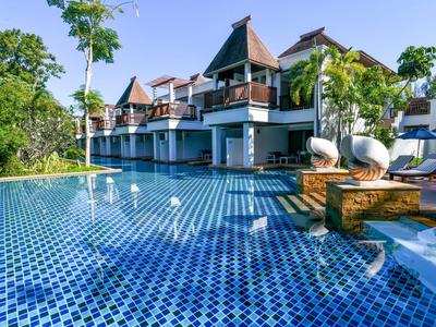 Großer blauer Pool mit Mosaikmuster vor einem modernen Hotel mit Balkonen und grünen Bäumen.