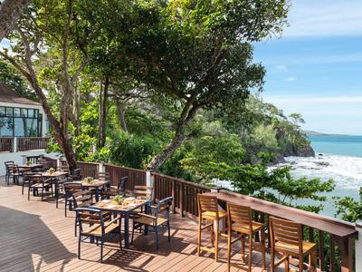 Terrasse mit Sitzgelegenheiten und Tischen mit Blick auf den Strand und das Meer.