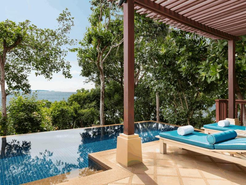 Privater Pool mit Sonnenliegen auf einer Terrasse mit Blick auf grüne Bäume und Wasser