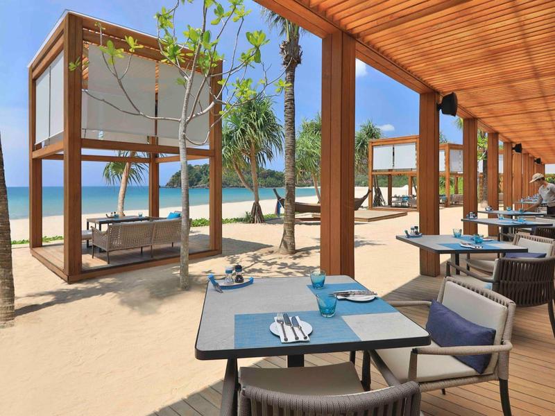 Strandrestaurant mit bequemen Sitzbereichen und Schlafkabinen aus Holz am Sandstrand.