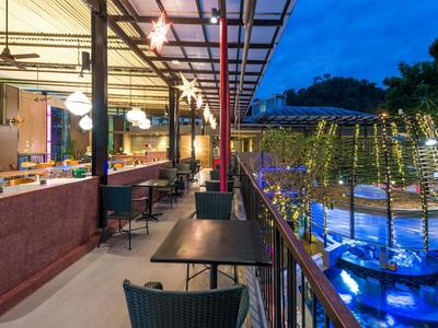 Balkonbereich eines Hotels mit Tischen und Stühlen, beleuchtet am Abend.