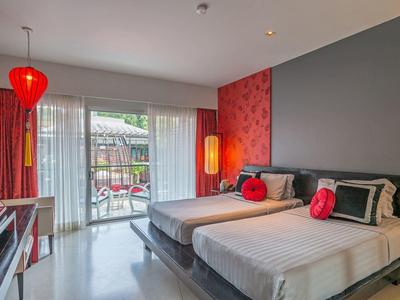 Modernes Hotelzimmer mit zwei Betten, roten Akzenten, grauer Wand und Balkon mit Blick nach draußen.