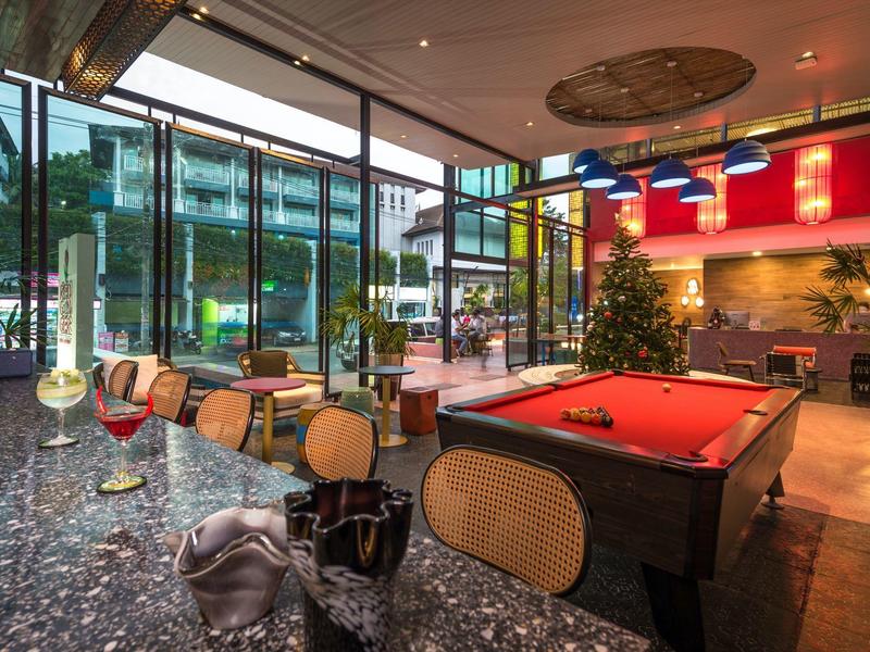 Moderne Hotellobby mit Billardtisch, Sitzgelegenheiten und großflächigen Fenstern mit Blick ins Freie.