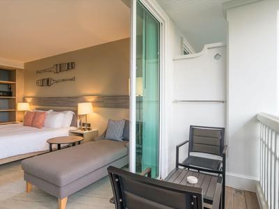 Hotelzimmer mit Doppelbett, Sitzecke und Balkon mit Stühlen und Tisch.