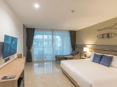 Modern eingerichtetes Hotelzimmer mit großem Bett, Flachbildschirm und Balkon.