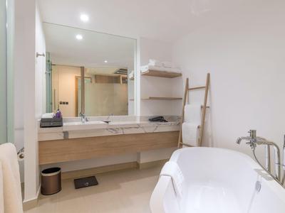 Modernes Badezimmer mit freistehender Badewanne, Holzregalen und großem Spiegel über dem Waschbecken.