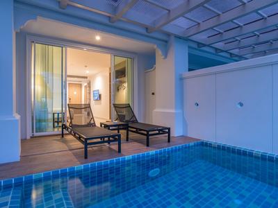 Moderner Außenbereich mit Pool und zwei Liegestühlen vor einer geöffneten Glasschiebetür.