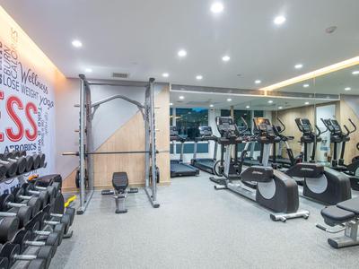 Heller Fitnessraum mit Hanteln, Kraftmaschinen und Cardiogeräten an den Wänden.