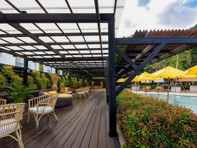 Outdoor-Bereich mit Pergola, Sitzgelegenheiten und Pool mit gelben Sonnenschirmen.