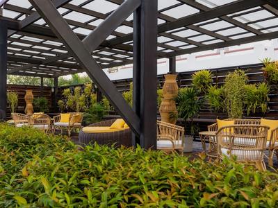 Gemütliche Außensitzplätze mit Holzmöbeln und Pflanzen unter einer Pergola.